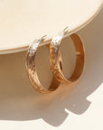 14k gold filled florence hoops resting on a stoneware plate in the sunlight