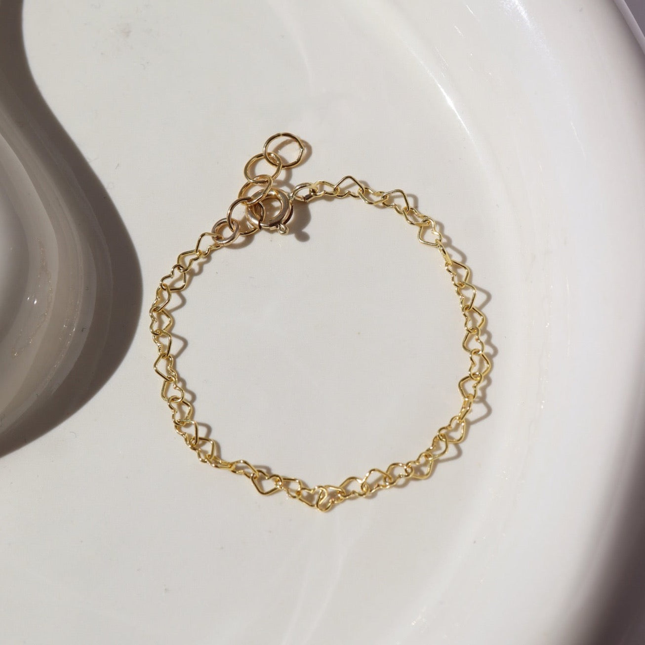 14k gold fill heart link chain in children's sizes, photographed on a ceramic white plate