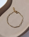 14k gold fill Tiny Clara Bracelet laid on a tan plate. This bracelet is made for children making it so that you and a child you know can match.