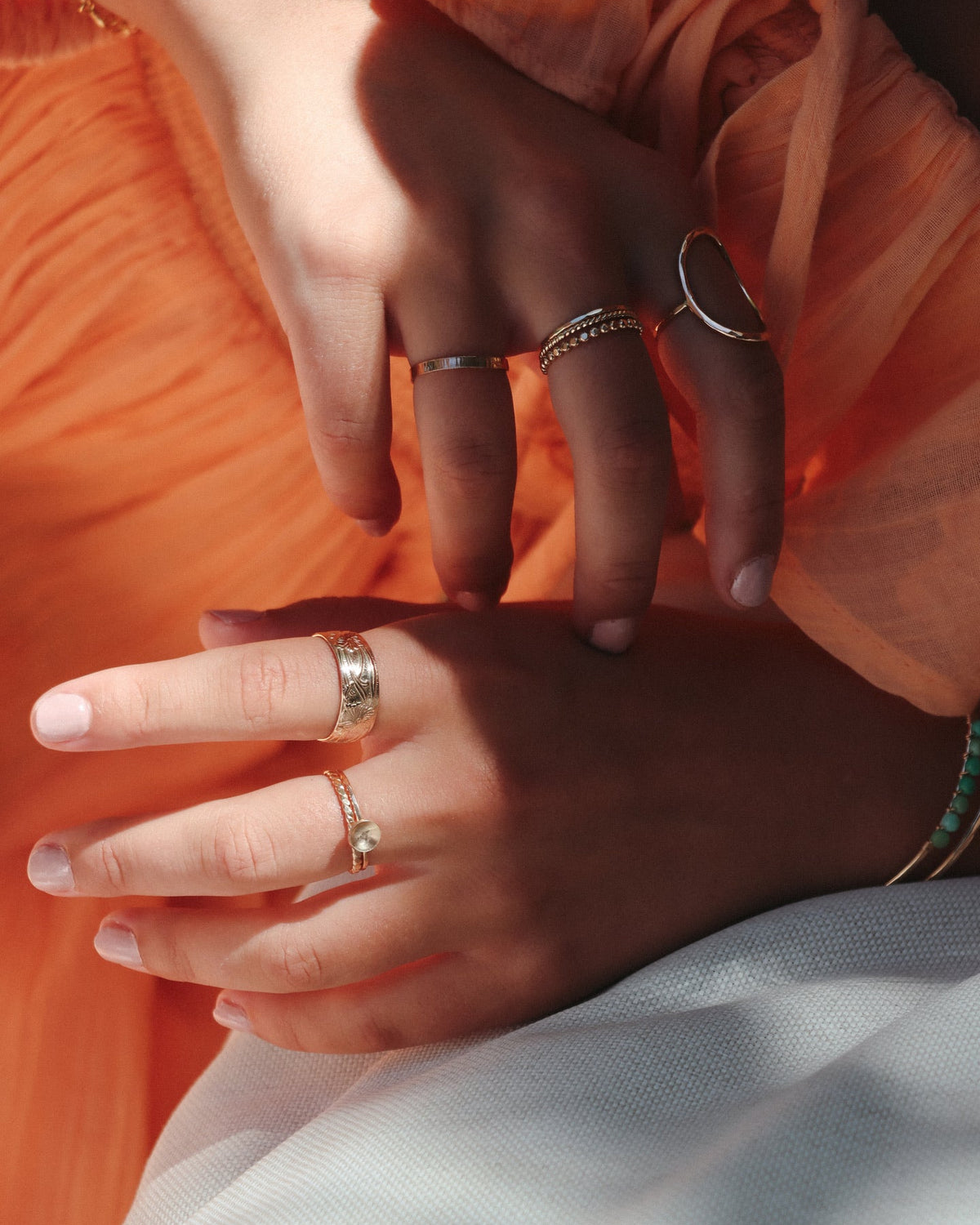 model wearing 14k gold fill textured band ring with delicate band with domed circle and other 14k gold fill 