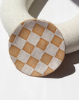 Ceramic Checkered jewelry dish laid against a white jewelry display. This is perfect to sit on your dresser and set your rings on. 