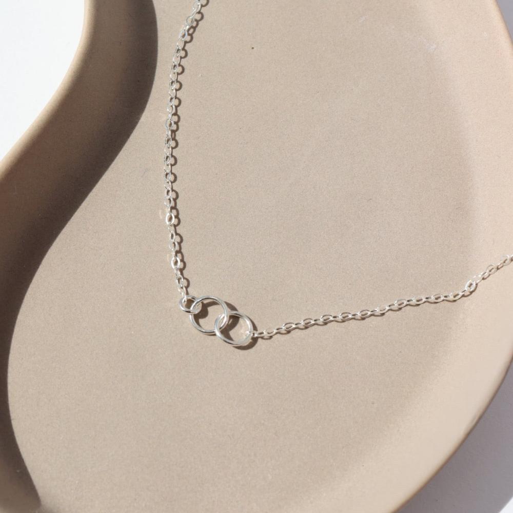 925 sterling silver Lineage Necklace laid on a tan plate in the sunlight