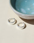 925 sterling silver Mia Huggies laid on a white plate in the sunlight