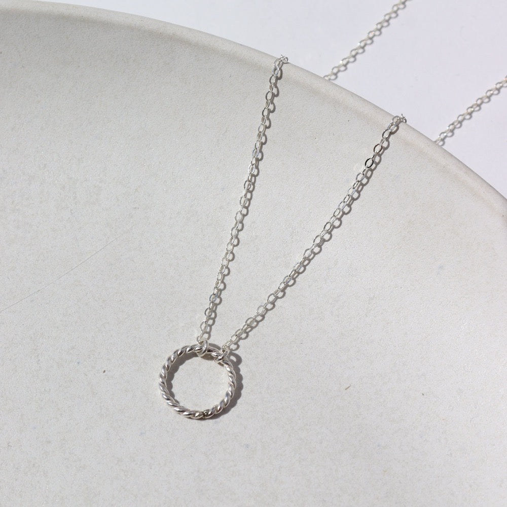 925 Sterling silver Spiral Necklace laid on a white plate. This necklace features the simple chain with the spiral eternity disc.