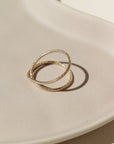 14k gold fill Sunburst Infinity ring laid on a tan plate In the sunlight.