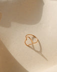 Gold heart-shaped ring on a textured beige surface