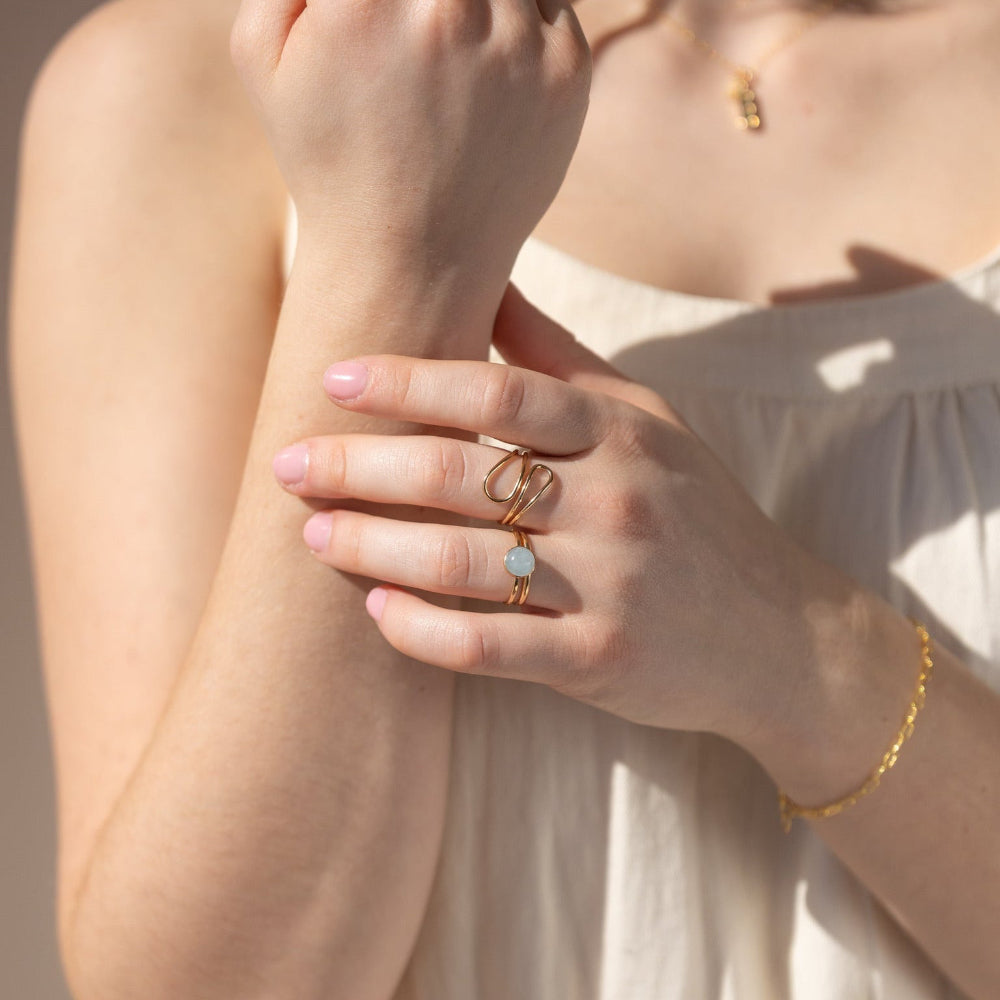 Close up of teardrop wrap ring  on a model in 14k gold fill stacked with pale blue 8mm Blue Lace Agate gemstone and simple stacking band. 