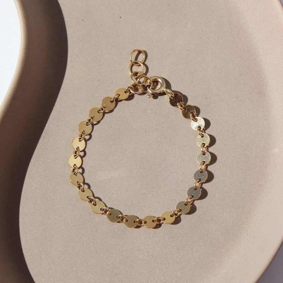 14k gold filled disc chain connected with small jump rings, photographed on a ceramic plate.