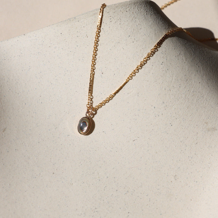 14k gold fill chain necklace with abalone stone pendant on a light dish