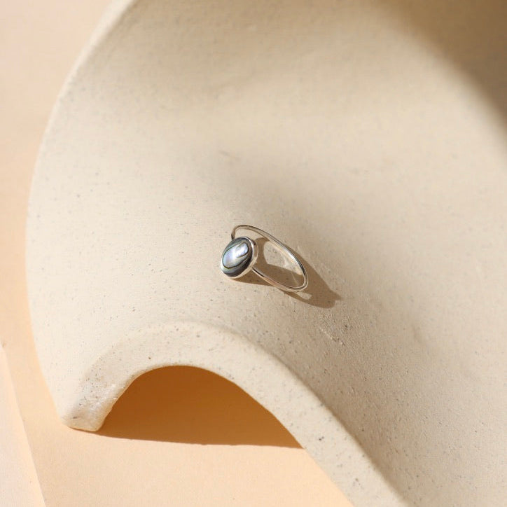 sterling silver ring with handset abalone stone on a light dish