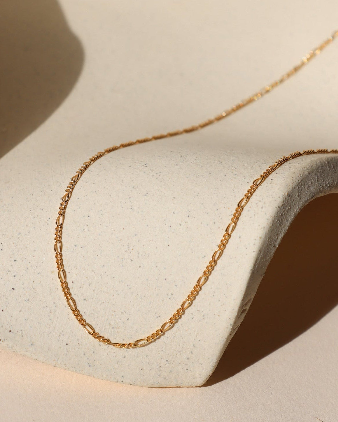 14k gold fill figaro chain necklace on a light dish