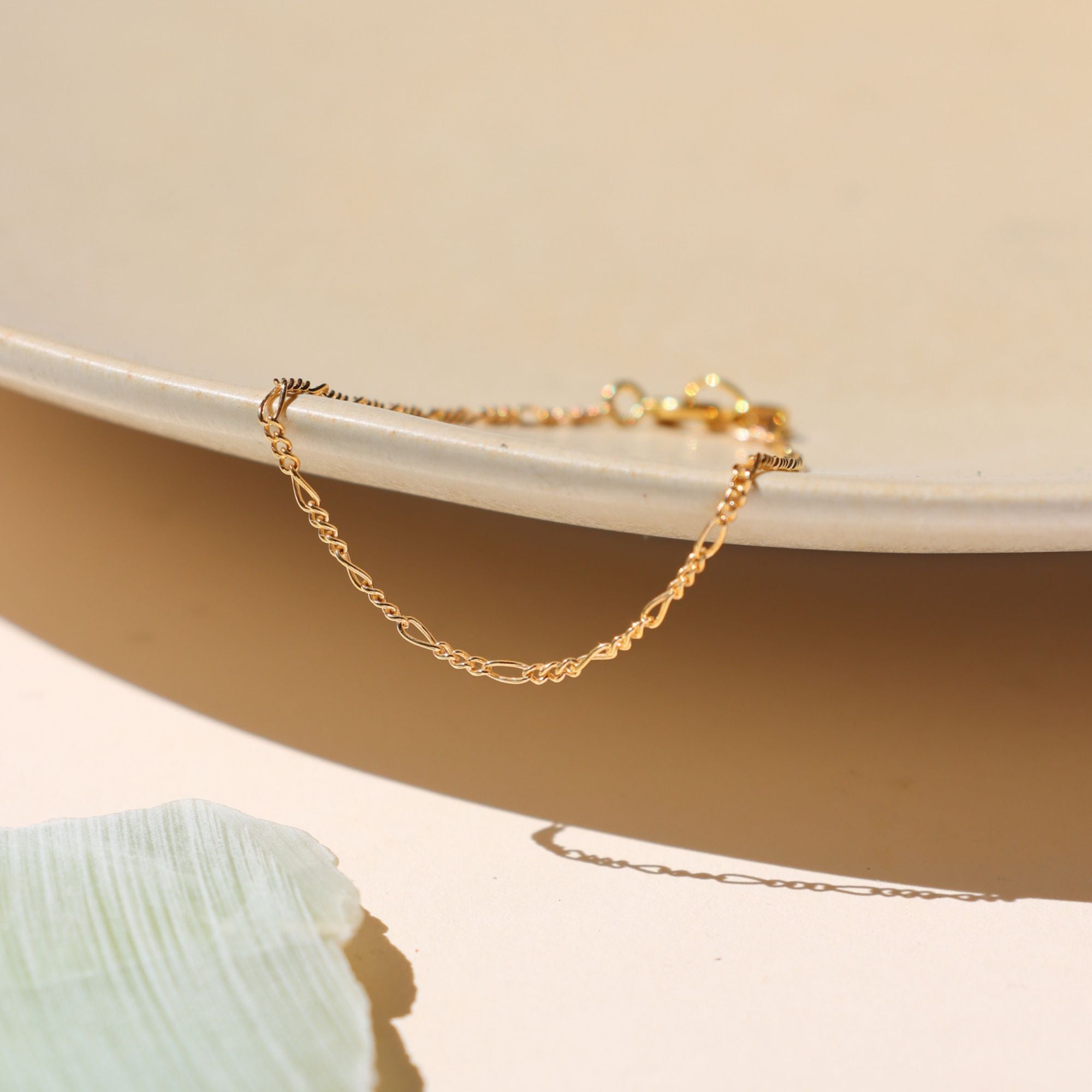 14k gold fill delicate figaro chain bracelet on a light surface