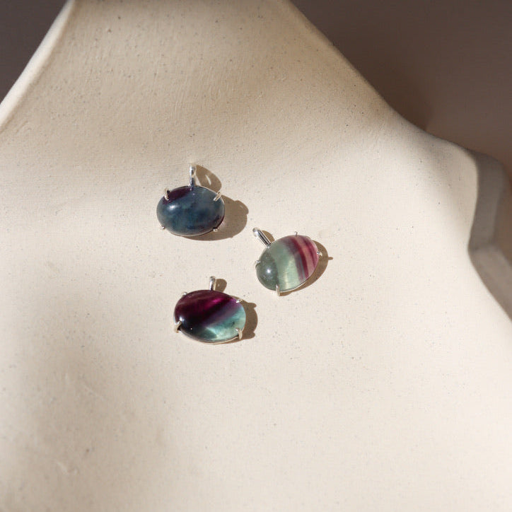 sterling silver bezel pendants with oval fluorite cabs on a light dish
