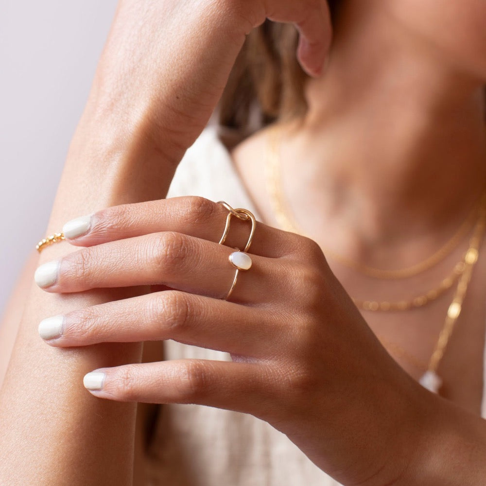 mother of pearl stone set in a bezel on a 14k gold fill skinny ring band, photographed on a model&#39;s hand