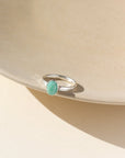 A 6x8mm amazonite gemstone set in a sterling silver serrated bezel. The ring is displayed on a cream dish. 