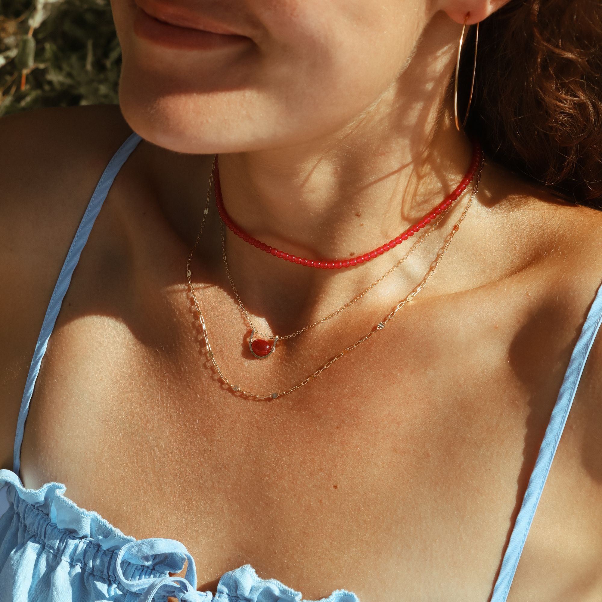 model wearing chain necklace, beaded ruby necklace and pendant necklace with ruby stone