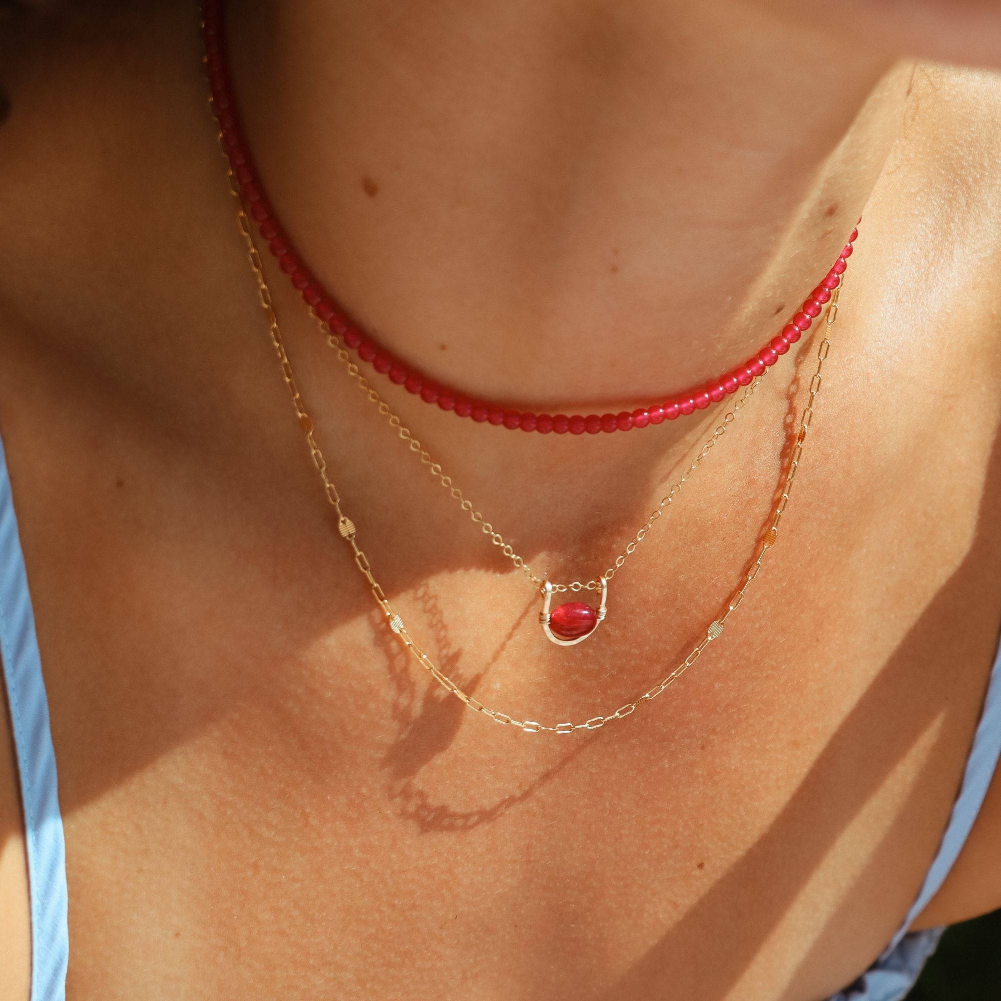 model wearing chain necklace, beaded ruby necklace and pendant necklace with ruby stone