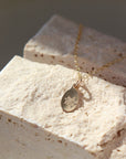 14k gold fill Birth Flower Necklace. Necklace laid across a cream stone. Handmade in Eau Claire Wisconsin. 