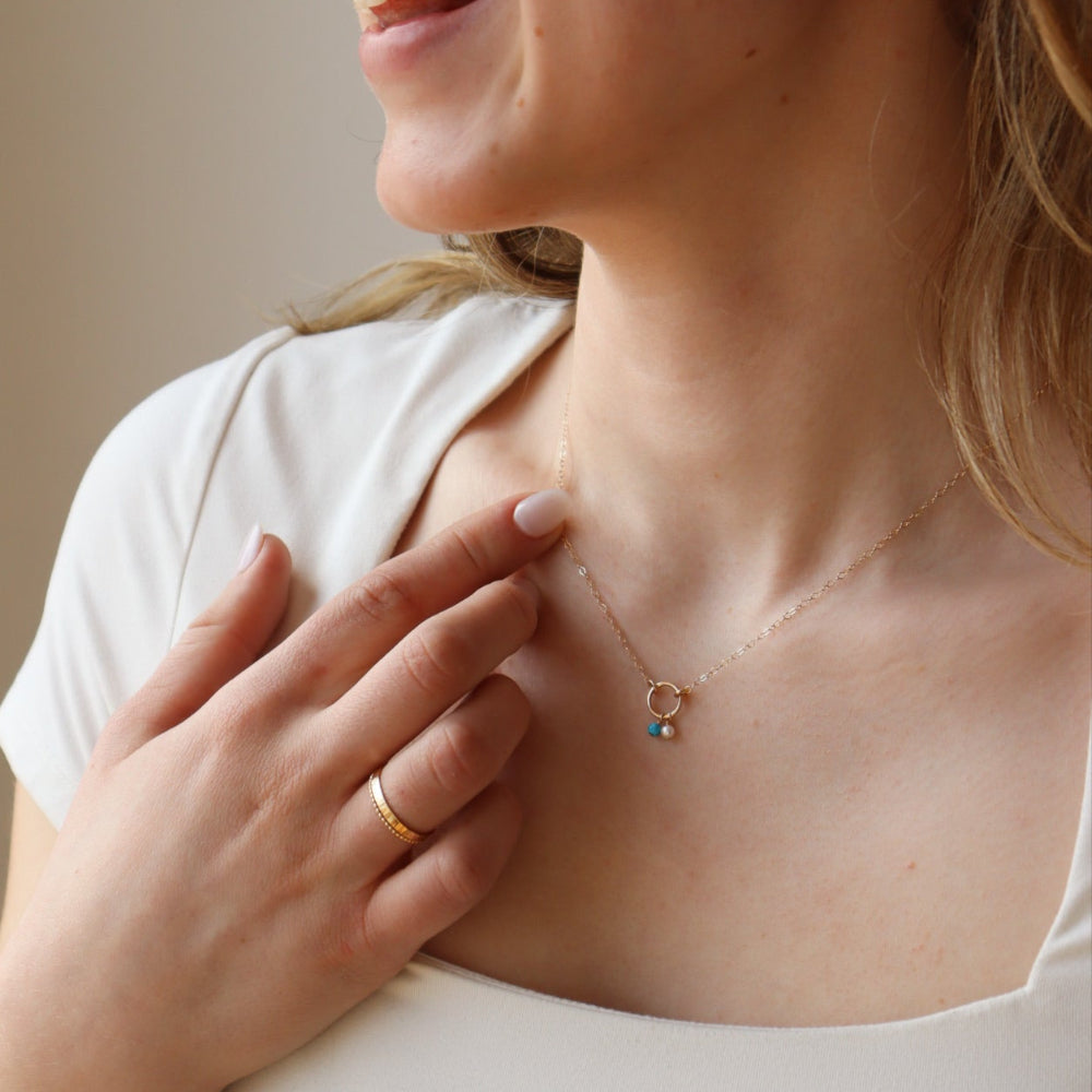 model wearing lightly hammered 14k solid gold circle pendent with dainty chain and colorful birthstone beads 