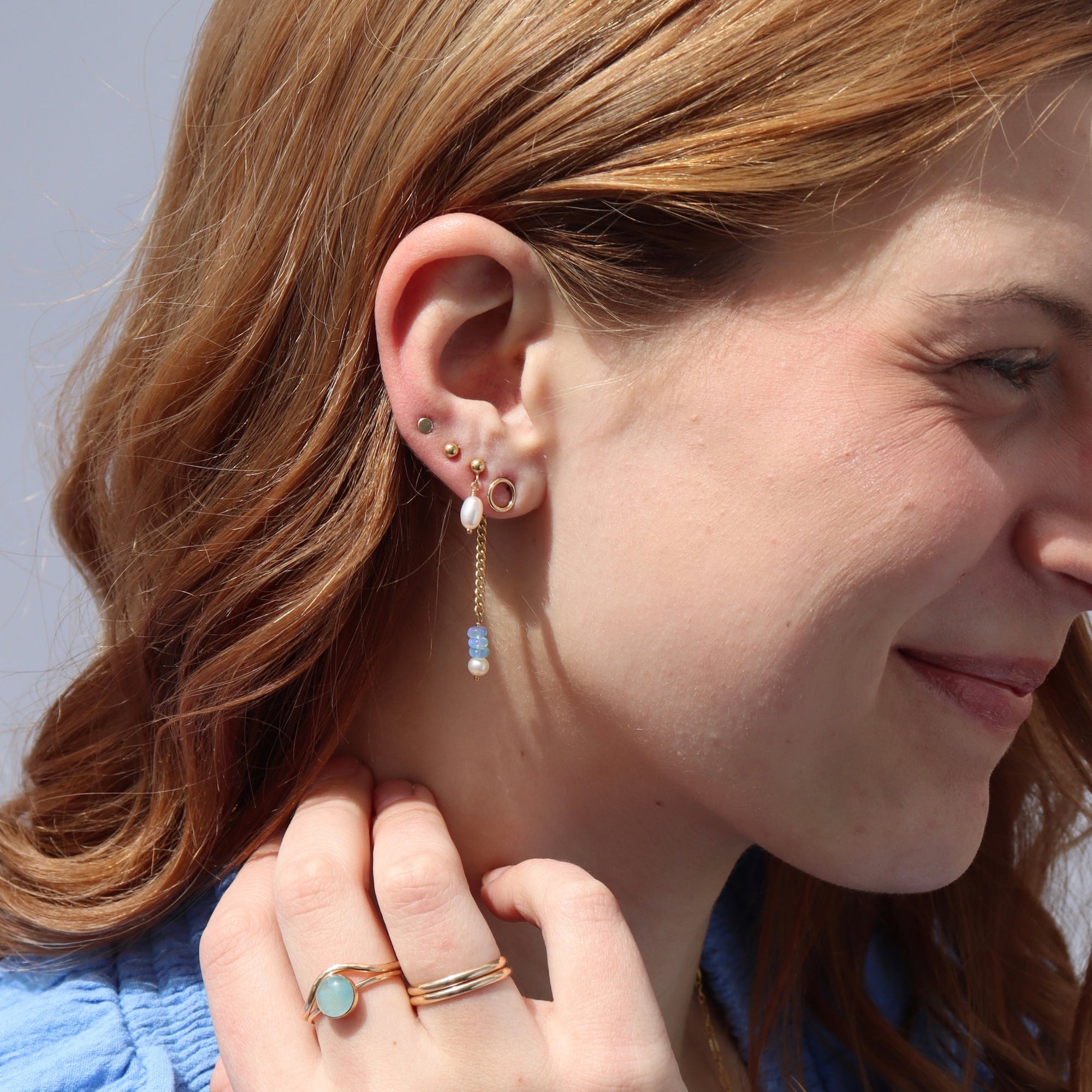 Model wearing a 14k gold fill back drop with a dainty curb chain, with three opal gemstones and one mini pearl set at the bottom