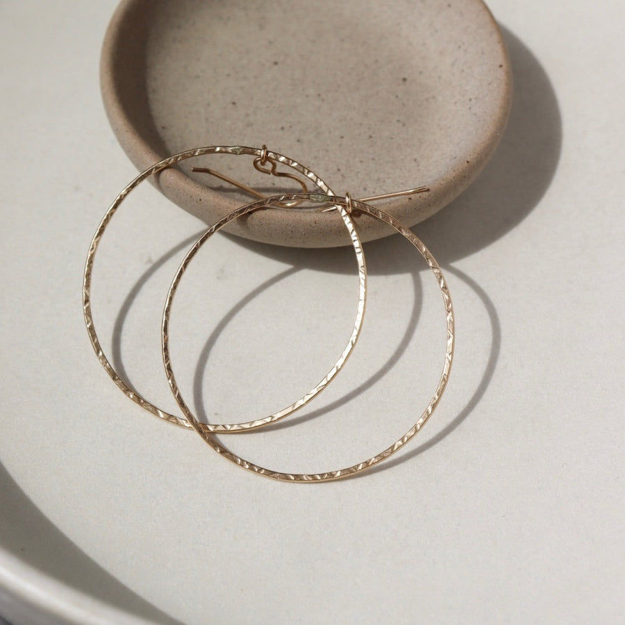 14k gold fill Soleil Hoops laid on a white paper in the sunlight