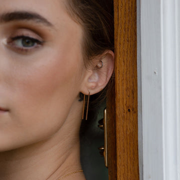 Model wearing 14k gold fill Staple Earring. A minimal earring that's perfect for everyday. Wear them in your second ear holes or let them be the main adornment for your ear lobes! Either way, these earrings will become one of your daily staples (pun, intended!).