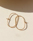 14k gold filled capsule hoops laid in the sun.