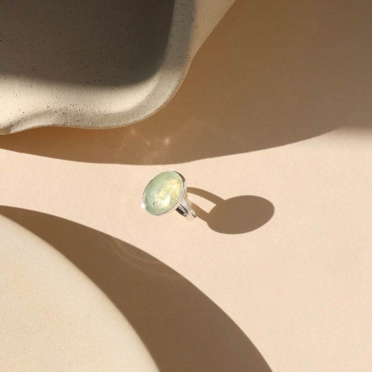 sterling silver bezel ring with prehnite stone on a light background
