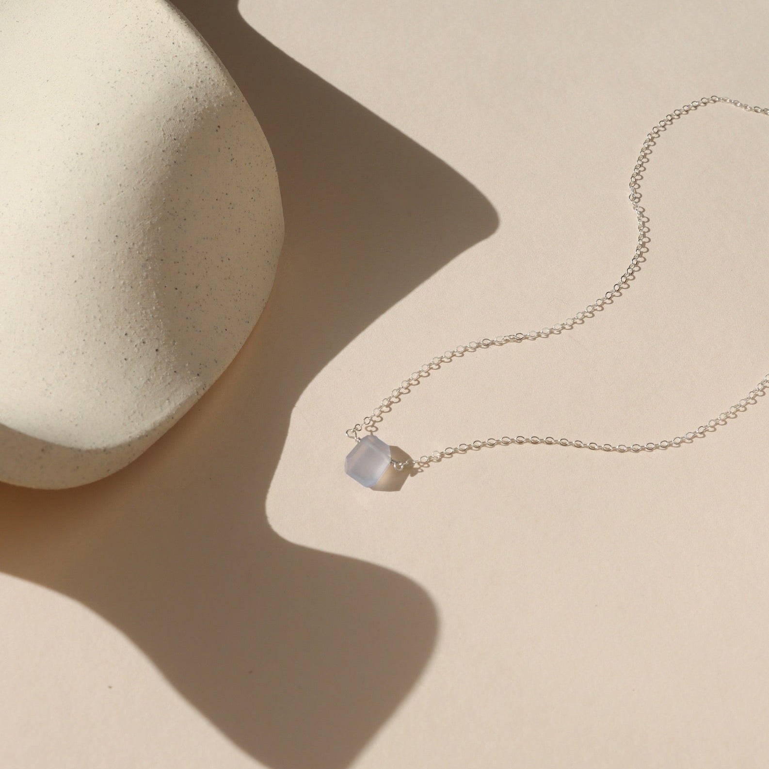 sterling silver simple chain with chalcedony stone wrapped in the center on a light dish