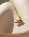 14k gold fill necklace with a thin standard chain with a cupid gold charm at the end of chain. Necklace is displayed on a white dish. 