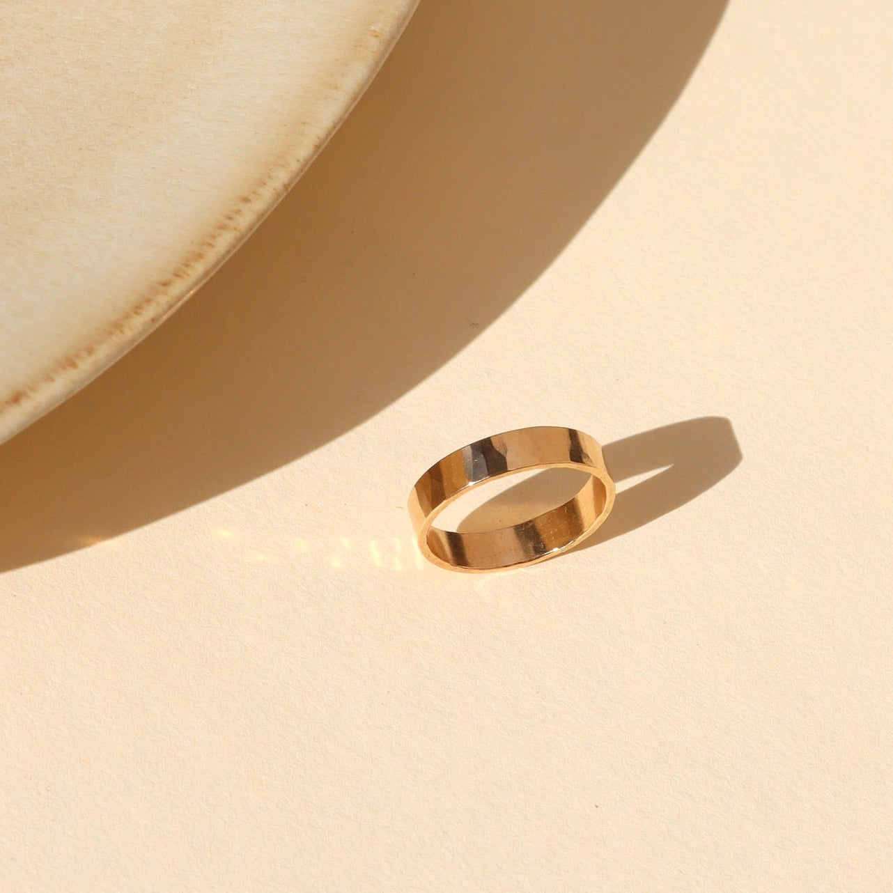 14k gold fill lightly hammered thick band ring on alight surface
