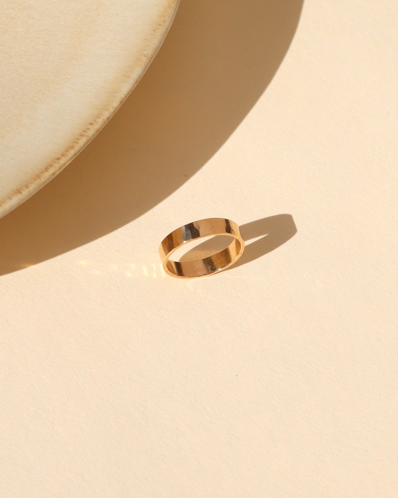 14k gold fill lightly hammered thick band ring on alight surface