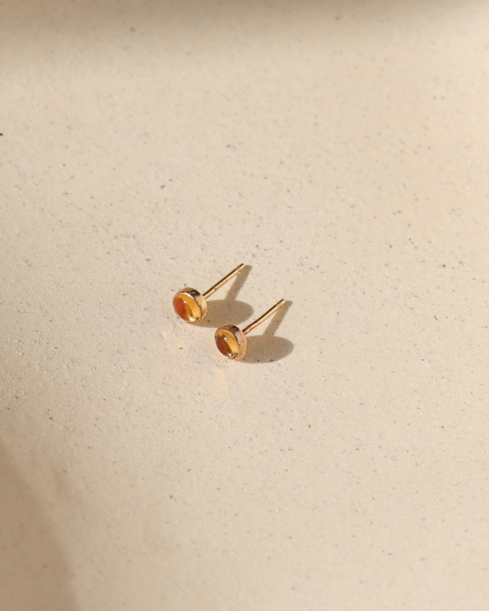 14k gold fill bezel ear posts with 4mm citrine stone on a light background