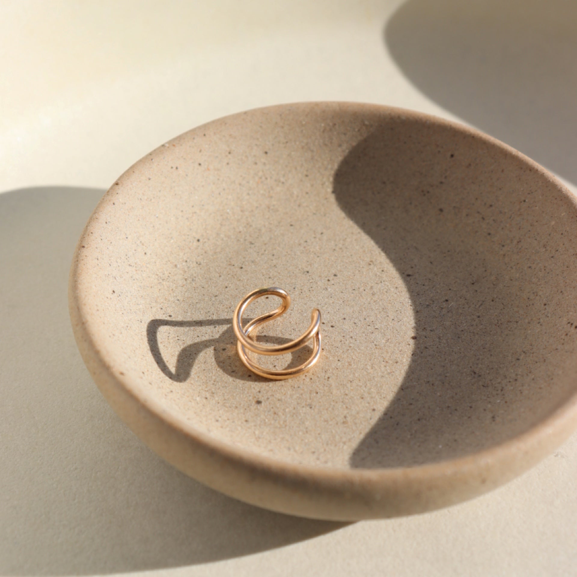 14k gold fill sculptural ear cuff on a light dish in the sunlight