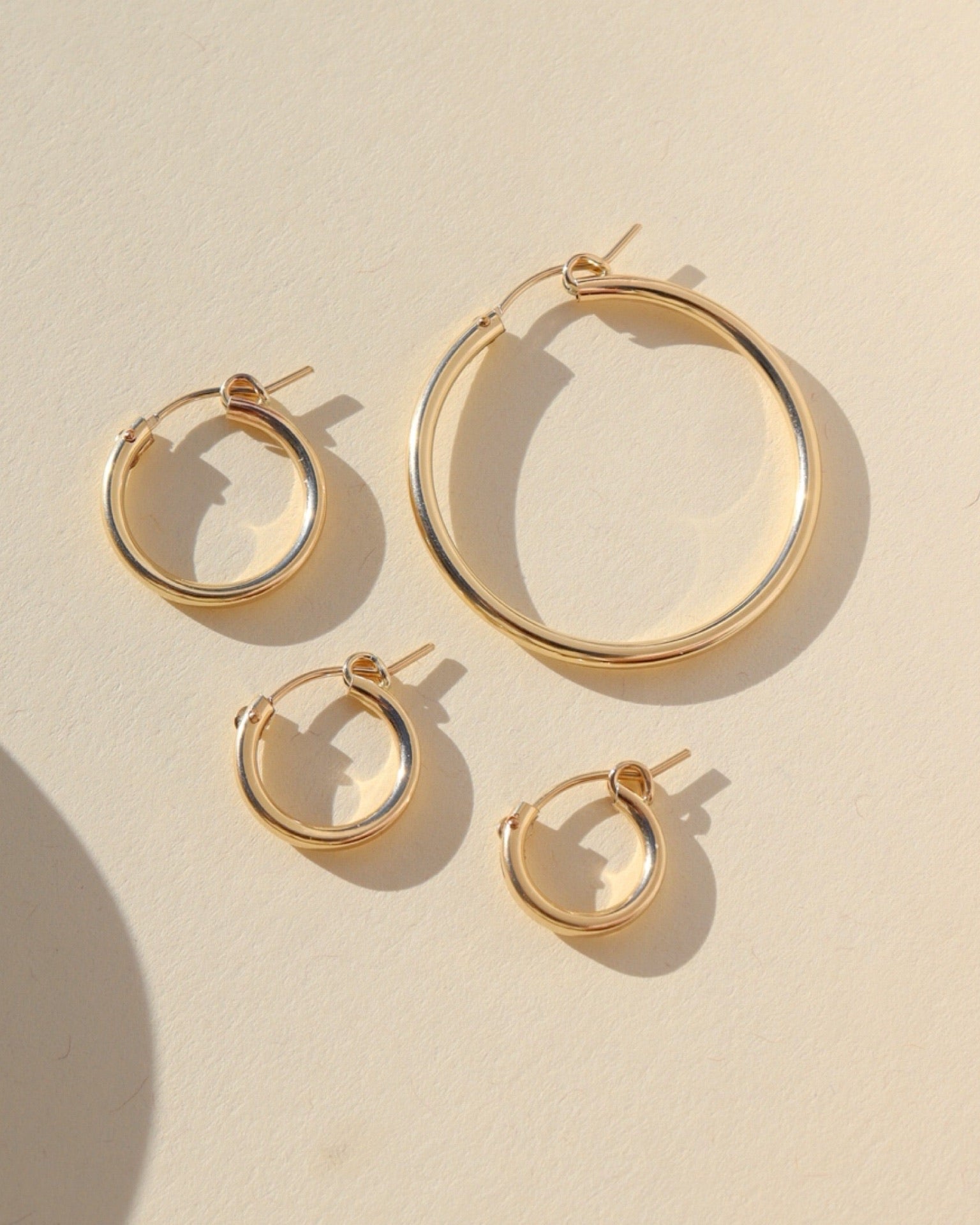 gold fill mini classic hoop, gold fill small classic hoop, gold fill medium classic hoop, gold fill large classic hoop laid in the sun