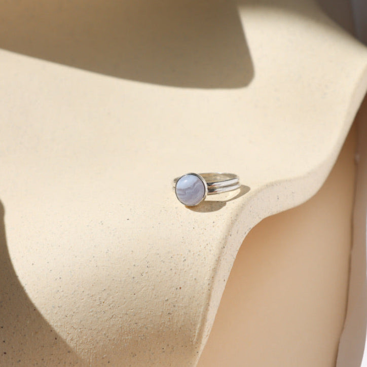 sterling silver double band bezel ring with round blue lace agate stone on a light dish