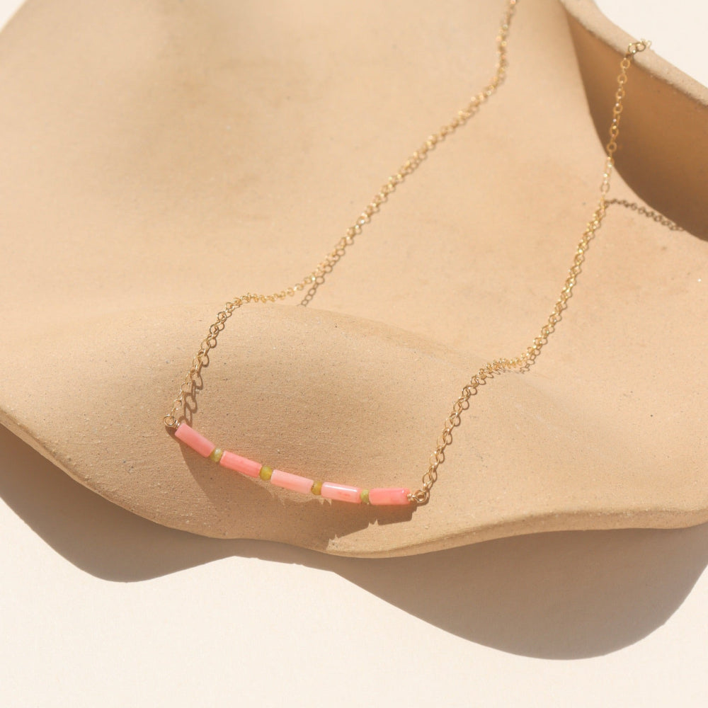 14k gold-filled necklace with five coral tube gemstones and serpentine beads, displayed on a tan dish.​