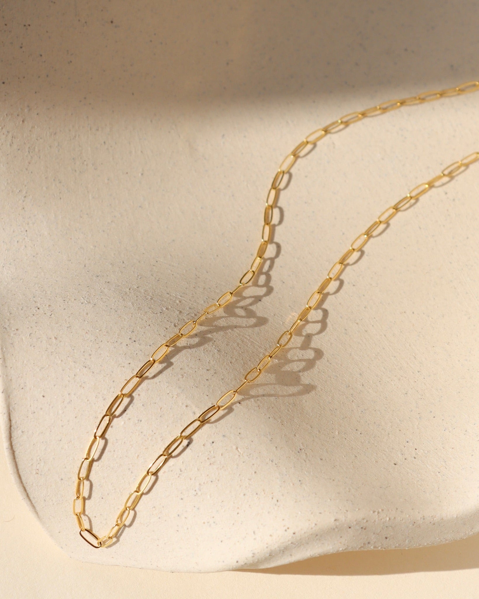 14k gold fill delicate cosette chain on wavy dish in the sunlight