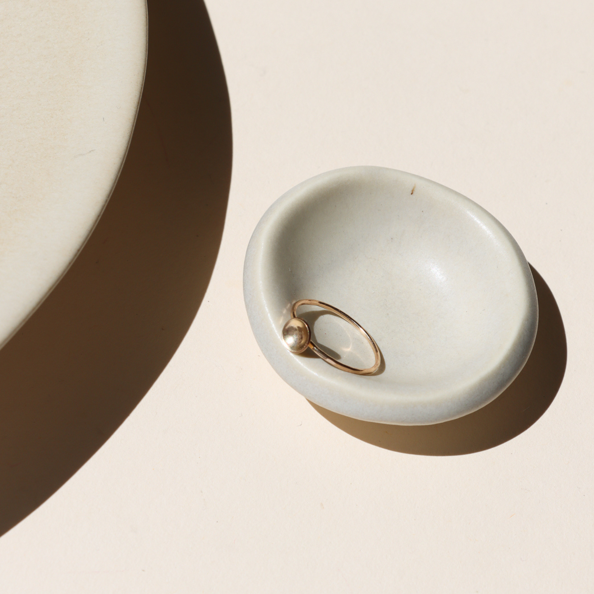 14k gold fill delicate band ring with curved disc on a light dish