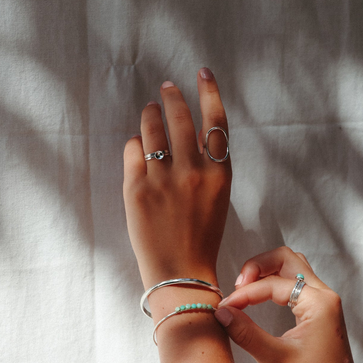 model wearing sterling silver delicate band ring with curved disc paired with other sterling silver jewelry