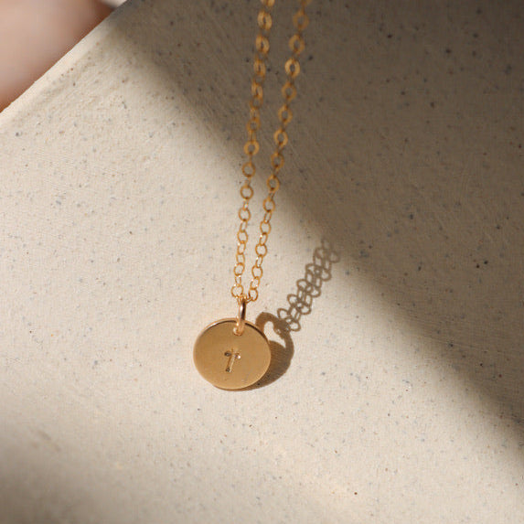 14k gold fill delicate chain necklace with a 14k gold fill hand stamped cross charm in the sunlight