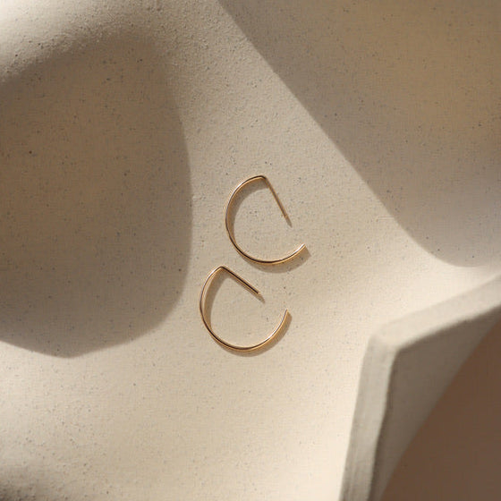 14k gold fill half circle shaped threader earrings on a light dish