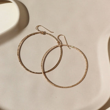 14k gold fill Soleil Hoops laid on a white paper in the sunlight