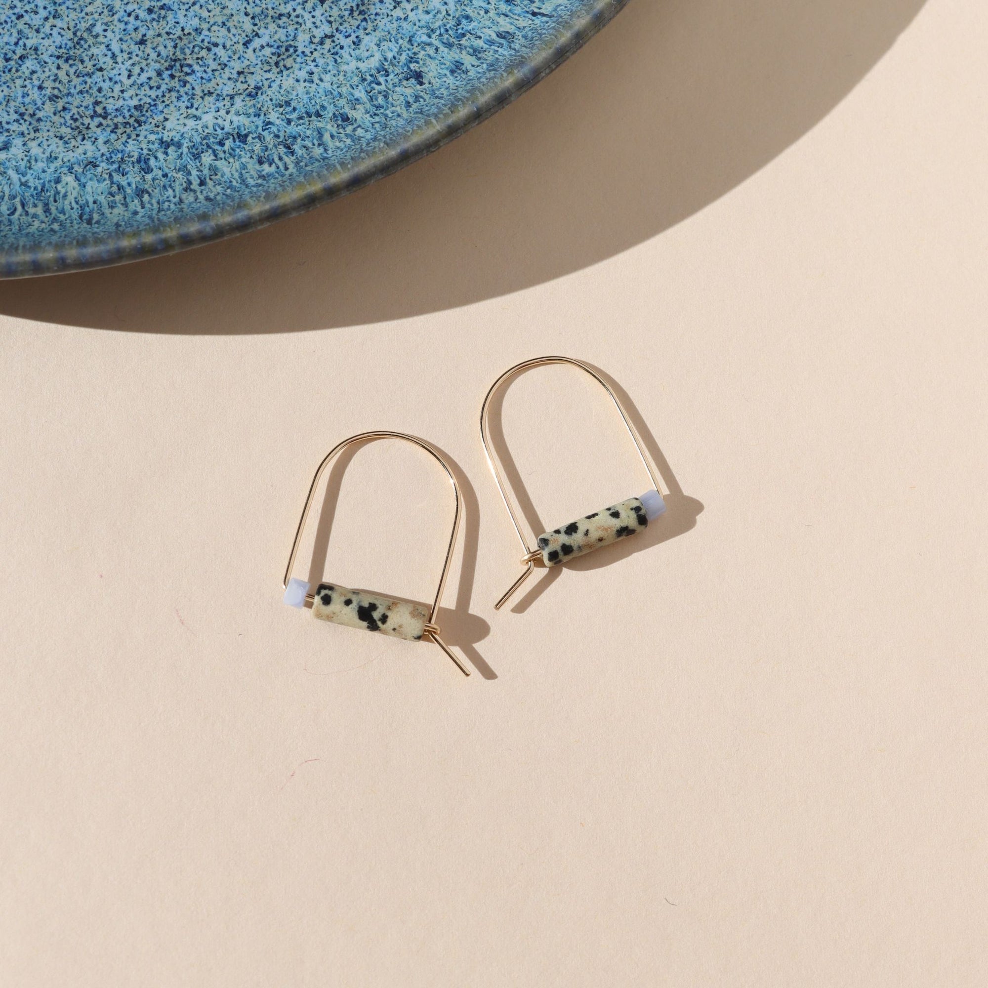 14k gold fill arch shaped earrings with dalmatian jasper & blue lace agate beads on a light background