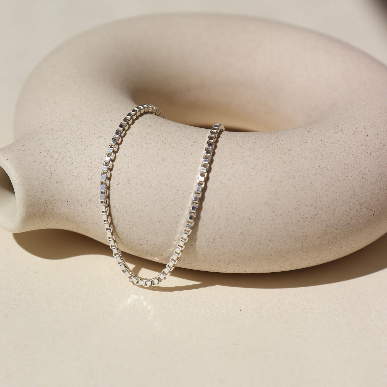 925 sterling silver Delaney anklet laid on a tan pot