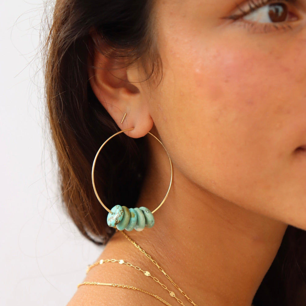 Model wearing Desert Sky Hoops featuring hammered gold filled with teal green turquoise bead accents.