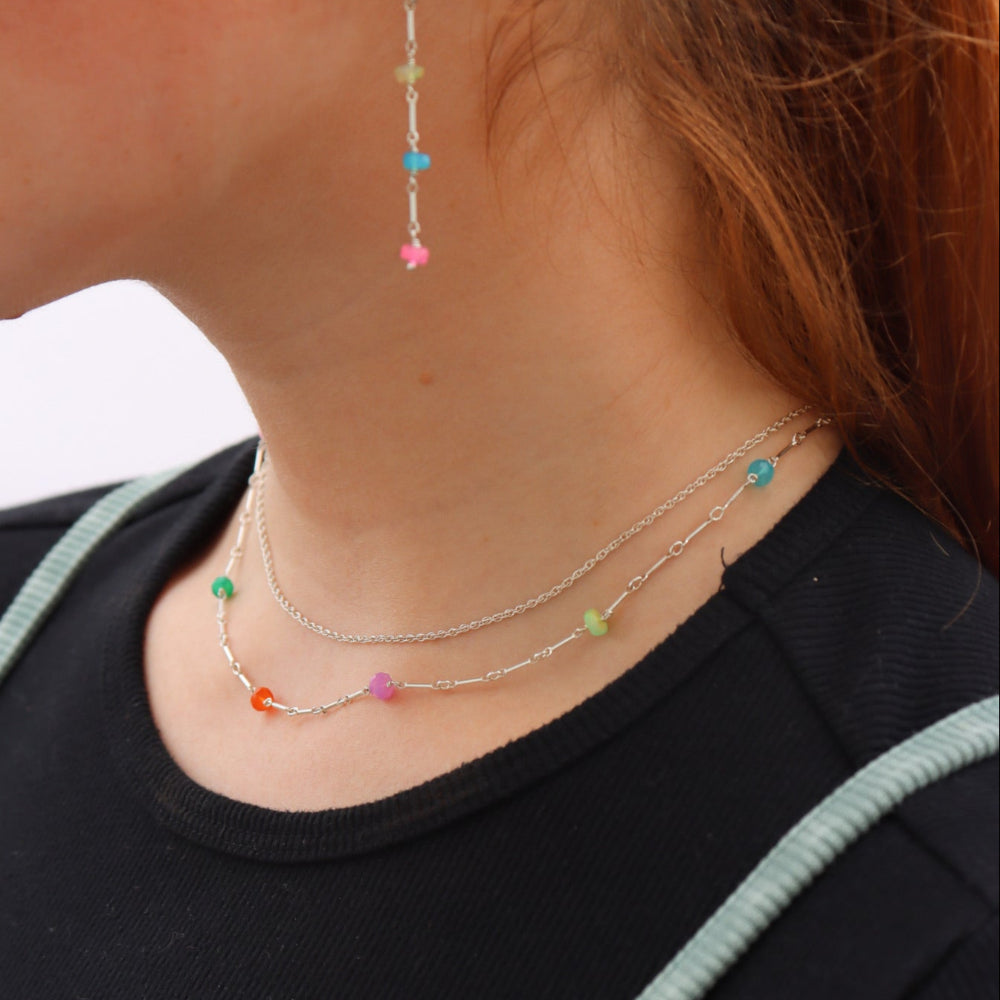 Model wearing sterling silver necklace featuring six vibrant opals and a textured chain with bar, dot, and dash links.