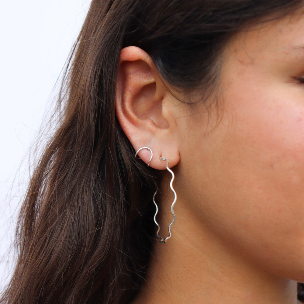 Model wearing a sterling silver hoop with wave-like textured wire