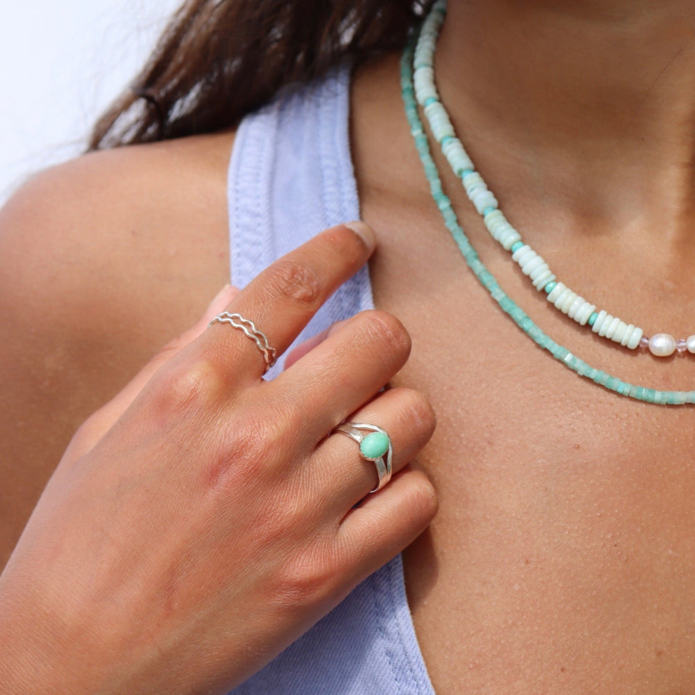 Model wearing two sterling silver rings with wave-like textured wire, model paired it with a amazonite gemstone ring set in sterling silver