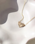 14k gold heart necklace on a 14k gold fill chain, photographed on a ceramic dish